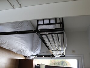 A bunk bed with white bedding, a wooden frame, and a window with a view of trees. - Bemelen Holiday Home for 6 (Bemelen)