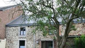 A stone building with a small entrance, a bench, and a tree in the foreground. - Winenne Home With Hot Tub (Beauraing)