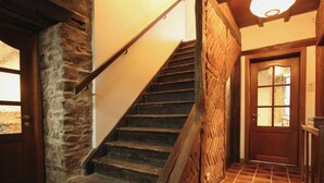 A staircase with stone walls and a wooden door with glass panels. - Winenne Home With Hot Tub (Beauraing)