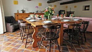 A dining area with a wooden table set for six, surrounded by six chairs. There is a sofa and a cabinet in the background. - Winenne Home With Hot Tub (Beauraing)