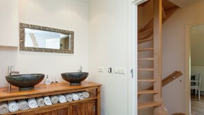 A bathroom with two vessel sinks, a wooden vanity with towels, a mirror, and a wooden staircase. - Scenic Gulp Valley Stay (Slenaken)