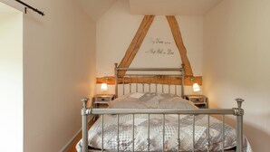 A bedroom with a metal bed frame, a wooden ceiling beam, two bedside lamps, and a wall with a decorative inscription. - Scenic Gulp Valley Stay (Slenaken)