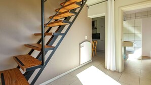 A modern staircase with wooden steps and metal railings, leading to a kitchen area with white cabinets and a tiled backsplash.