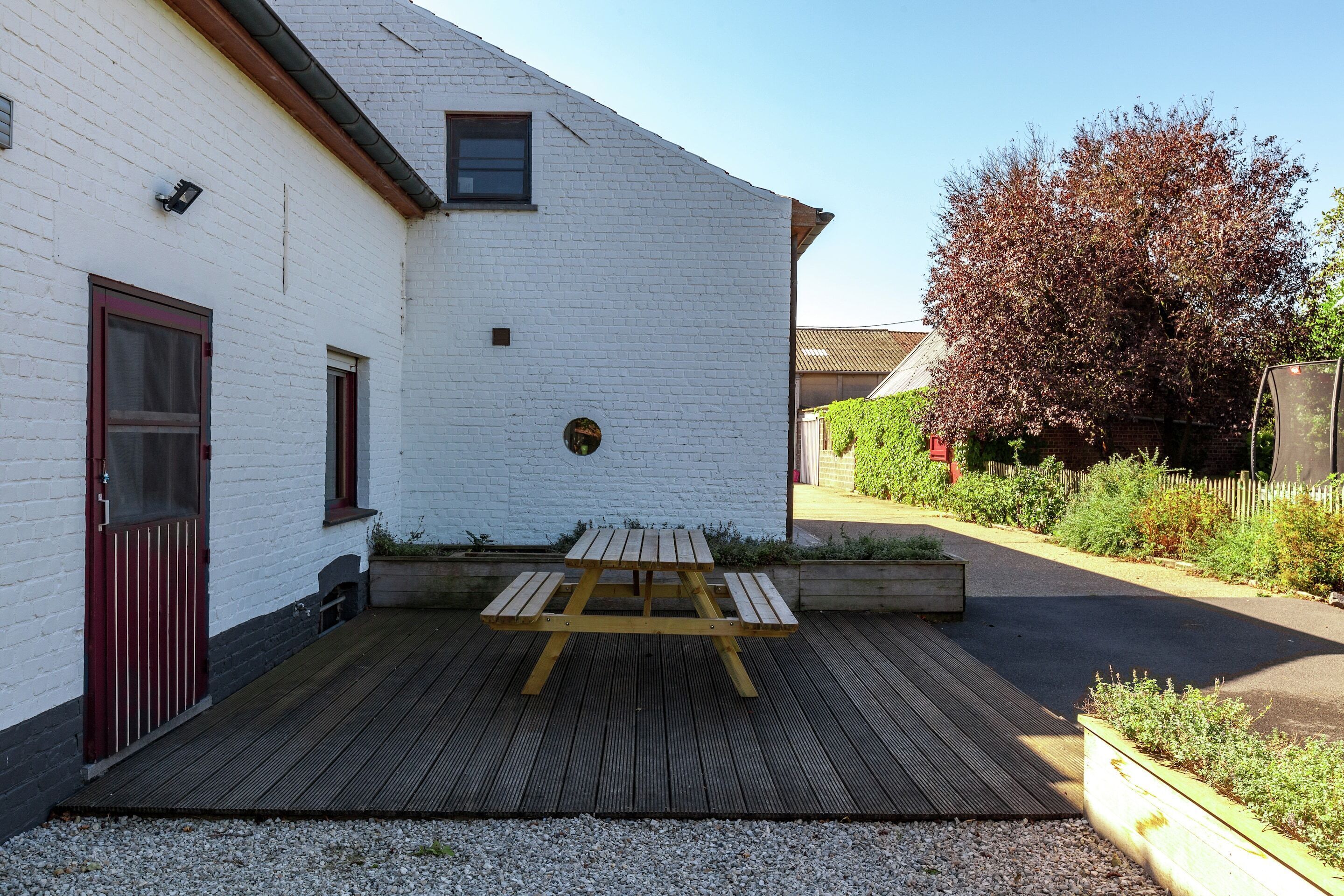 Un edificio de ladrillo blanco con una mesa de picnic de madera en el patio.