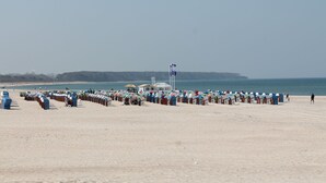 A beach with rows of beach huts and a lifeguard tower. - Apartment With Parasol in Sudstadt (Rostock)