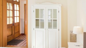 A hotel room with a bed, a nightstand with a lamp, a wardrobe, and a checkered floor. - Chic Apartment in Hessisch Oldendorf (Hessisch Oldendorf)