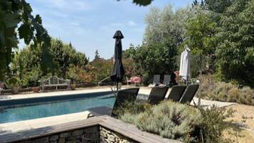 A pool area with lounge chairs and a stone wall.