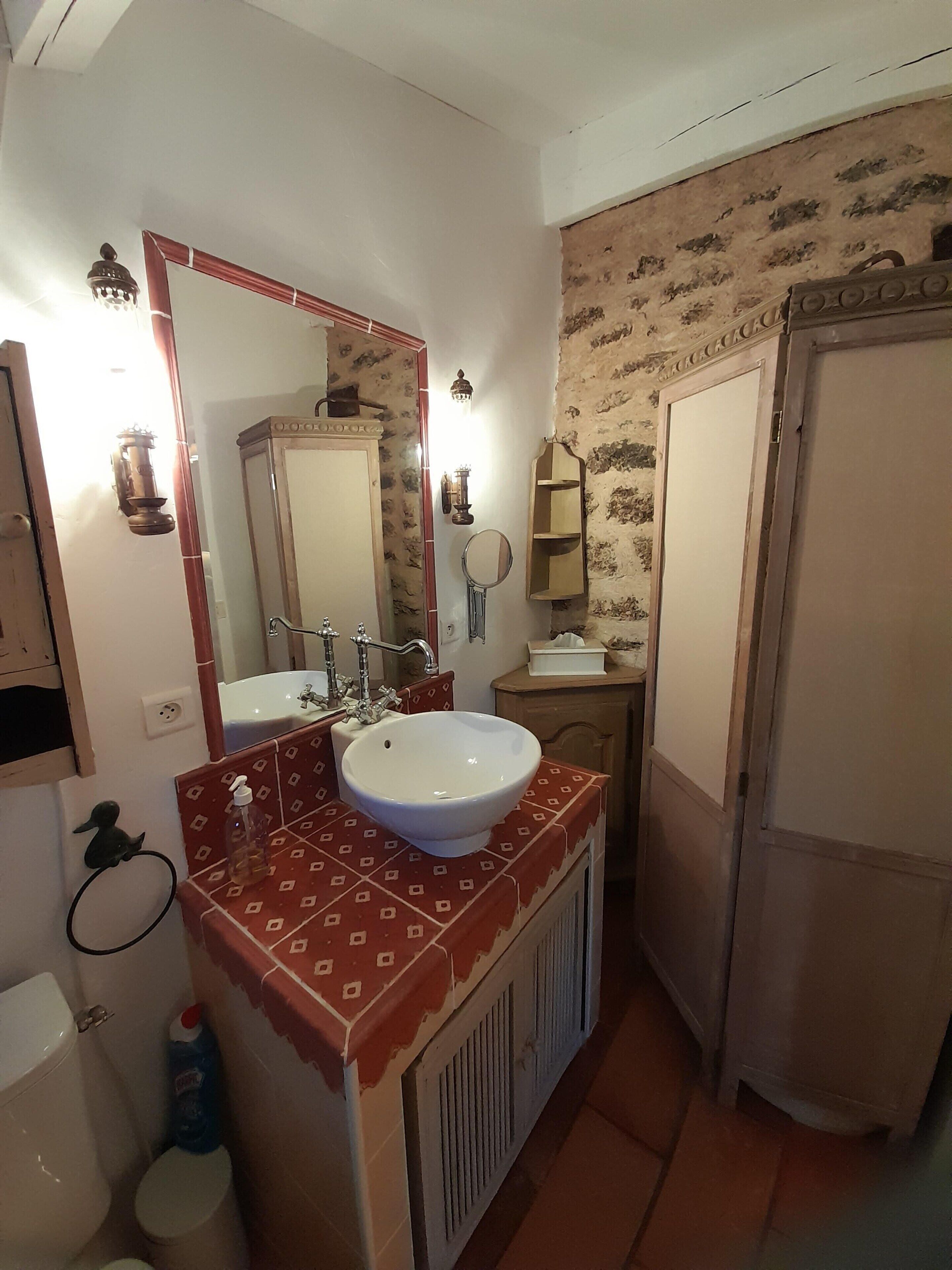 Un baño con lavamanos blanco, un espejo, toallero y un inodoro.