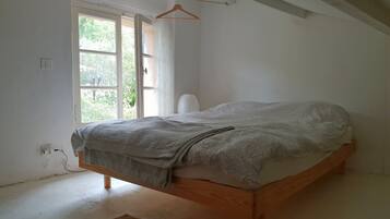 Une chambre avec un lit en bois, une fenêtre avec des rideaux et un luminaire suspendu.