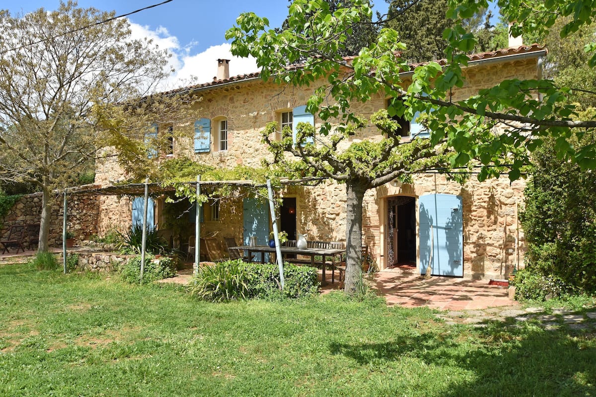 Un bâtiment en pierre doté d’un patio couvert et d’une table.