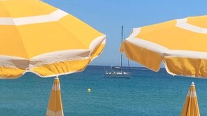 Two yellow beach umbrellas with white trim, set against a clear blue sea and a sailboat in the background. - Farmhouse, With Large pvt Pool in Provence (Draguignan)