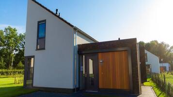 A modern two-story building with a large wooden door and a small window on the upper floor.
