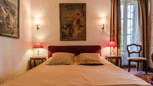 Une chambre à coucher avec un grand lit, deux lampes de chevet, une chaise et un tableau au mur.