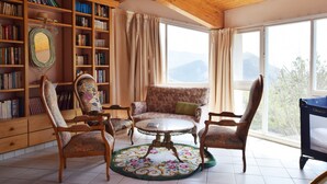 Ein gemütliches Zimmer mit Holzboden, einem runden Tisch, einer Couch und einem Bücherregal voller Bücher.