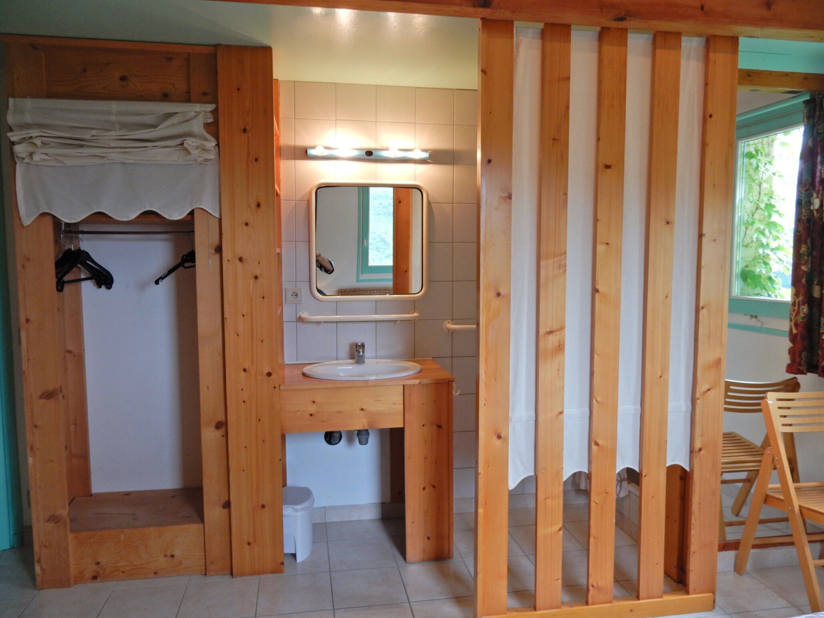 A wooden bathroom with a sink, mirror, and towel rack.