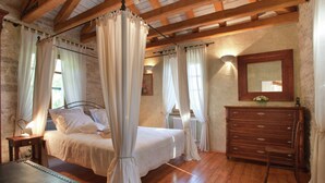 A bedroom with a four-poster bed, wooden floor, stone walls, and a dresser. - Authentic Holiday Home in Barban With Swimming Pool (Rasa)