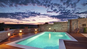 A rooftop pool area with stone walls and wooden deck, surrounded by chairs and potted plants. - Authentic Holiday Home in Barban With Swimming Pool (Rasa)