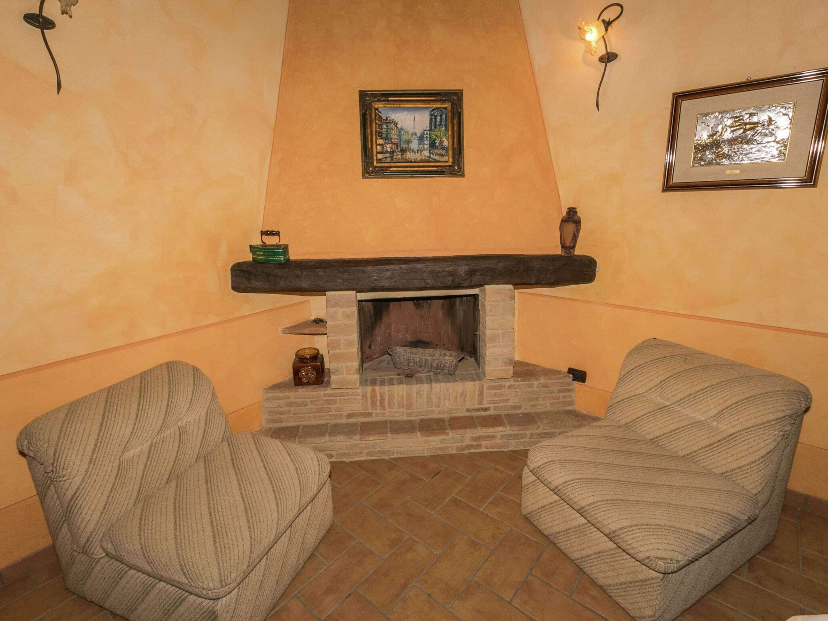 A cozy living room with a fireplace, two striped armchairs, and a framed picture on the wall.