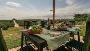 An outdoor dining area with a table set for four, surrounded by chairs, under a large umbrella. - Luxury, Modern Apartment With Pool and Stunning Views (Narni)