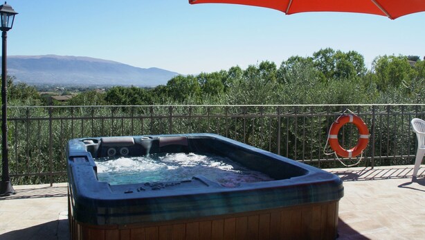 A hot tub with an umbrella, a lifebuoy, and a view of mountains. - Holiday Home in Bettona With Pool & Near Assisi (Bettona)