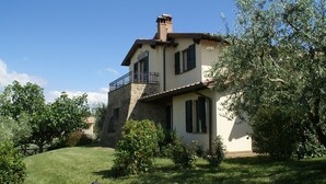 A two-story house with a stone facade, a balcony, and a well-maintained lawn. - Holiday Home in Bettona With Pool & Near Assisi (Bettona)