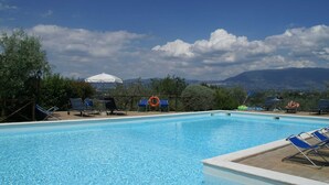 A swimming pool with lounge chairs and umbrellas, surrounded by trees and mountains in the background. - Holiday Home in Bettona With Pool & Near Assisi (Bettona)