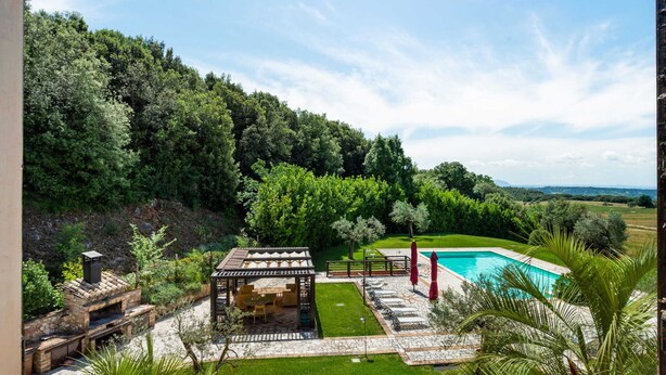 A poolside area with a pergola, seating, and a view of a forested hillside. - Luxury, Modern Apartment With Pool and Stunning Views (Narni)