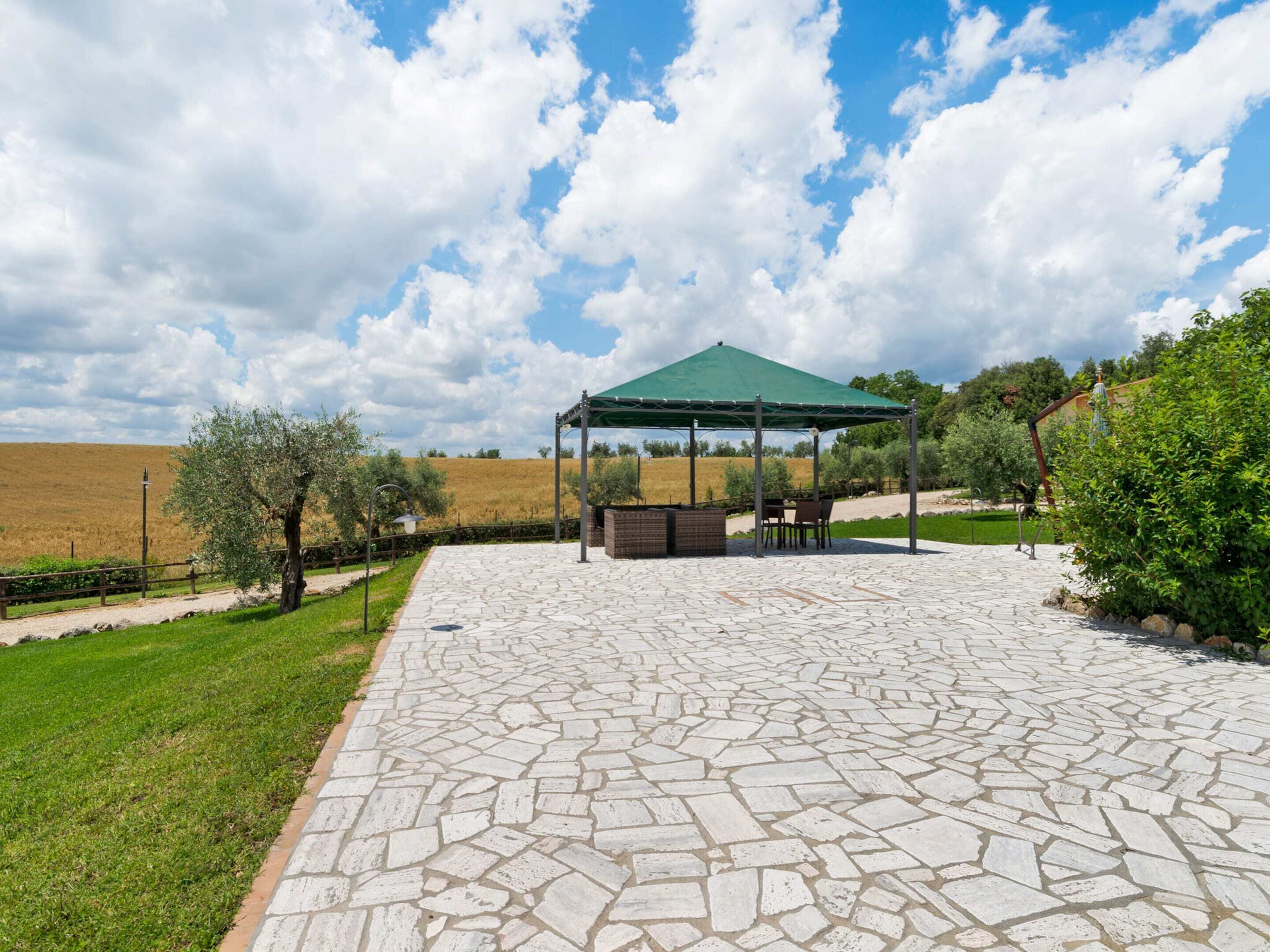 A covered outdoor seating area with stone flooring and a green canopy.