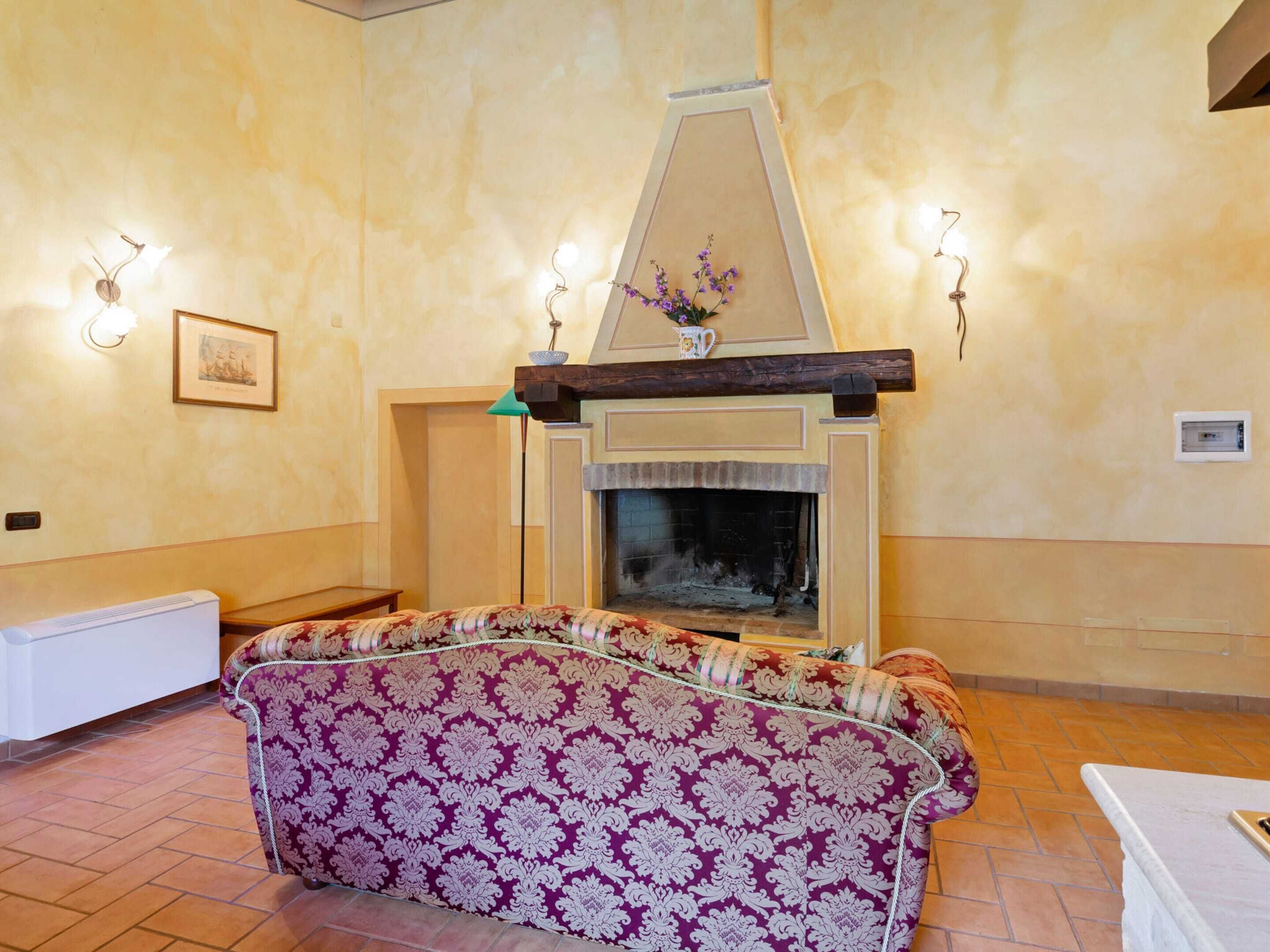 A living room with a fireplace, a patterned sofa, and wall sconces.