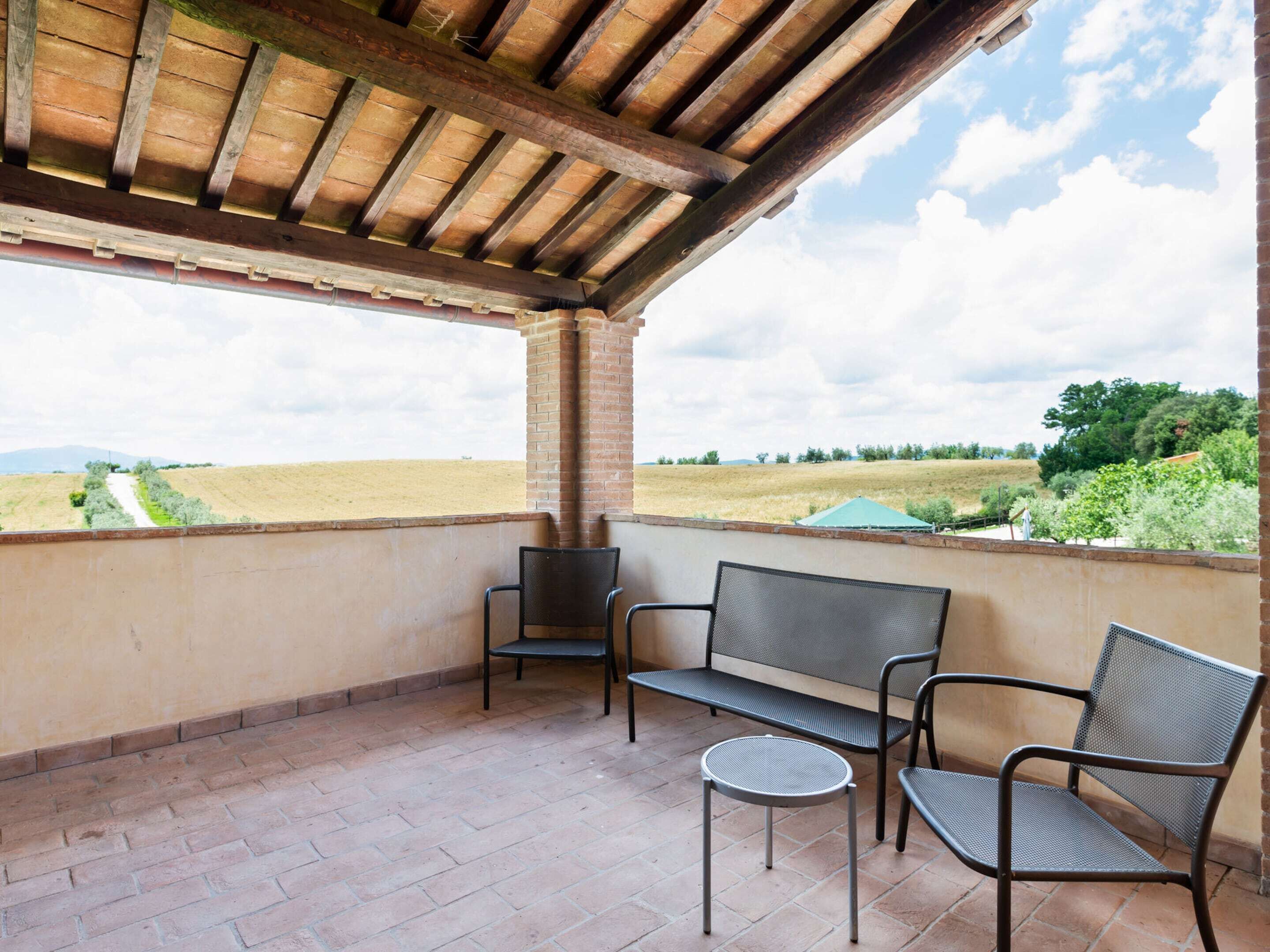 A covered outdoor seating area with a view of a field and trees.