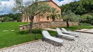 A stone building with a sloped roof, surrounded by a well-maintained lawn and a stone wall. - Luxury, Modern Apartment With Pool and Stunning Views (Narni)