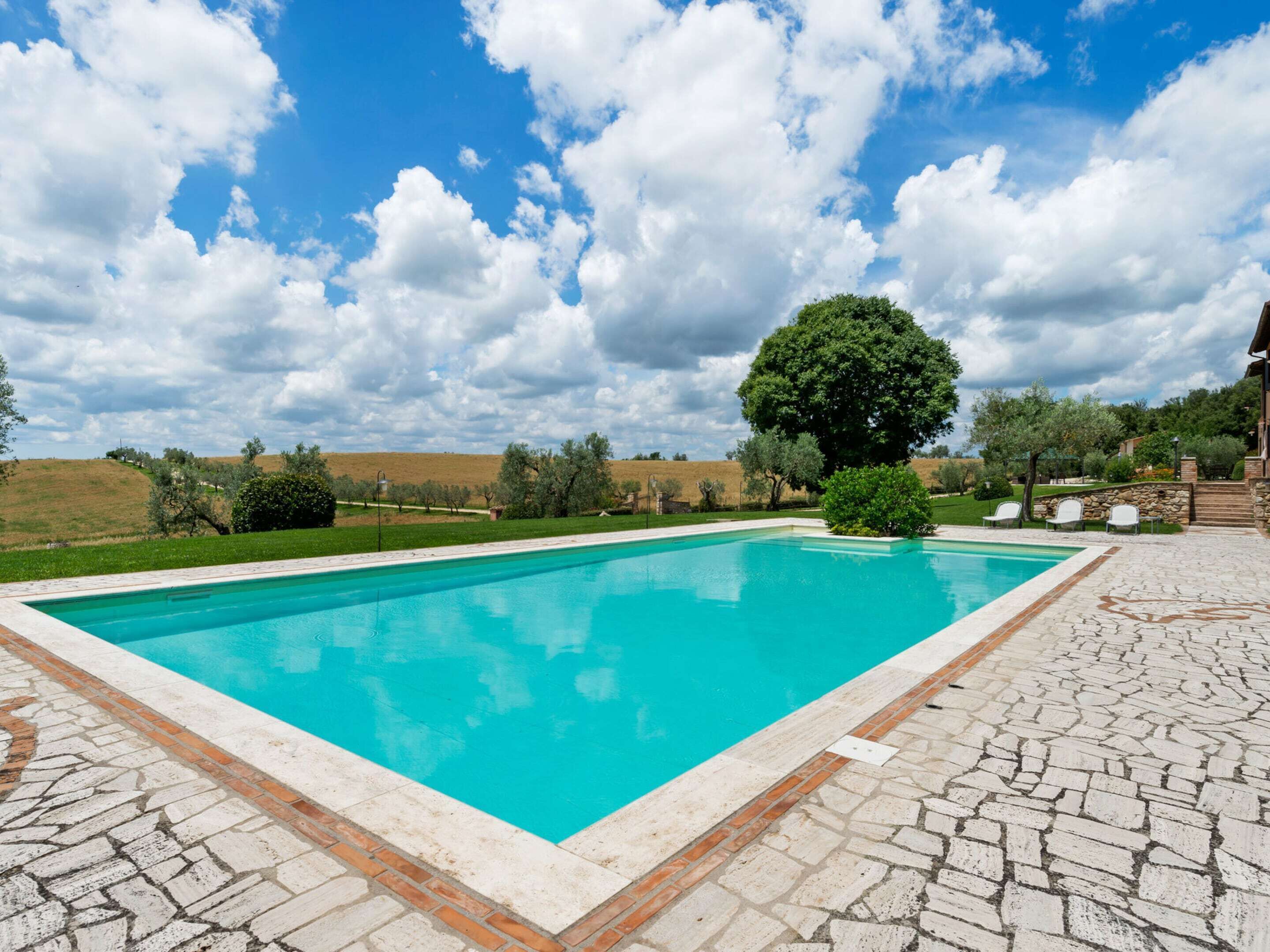 A rectangular swimming pool with a clear blue water surface, surrounded by a stone-tiled deck.
