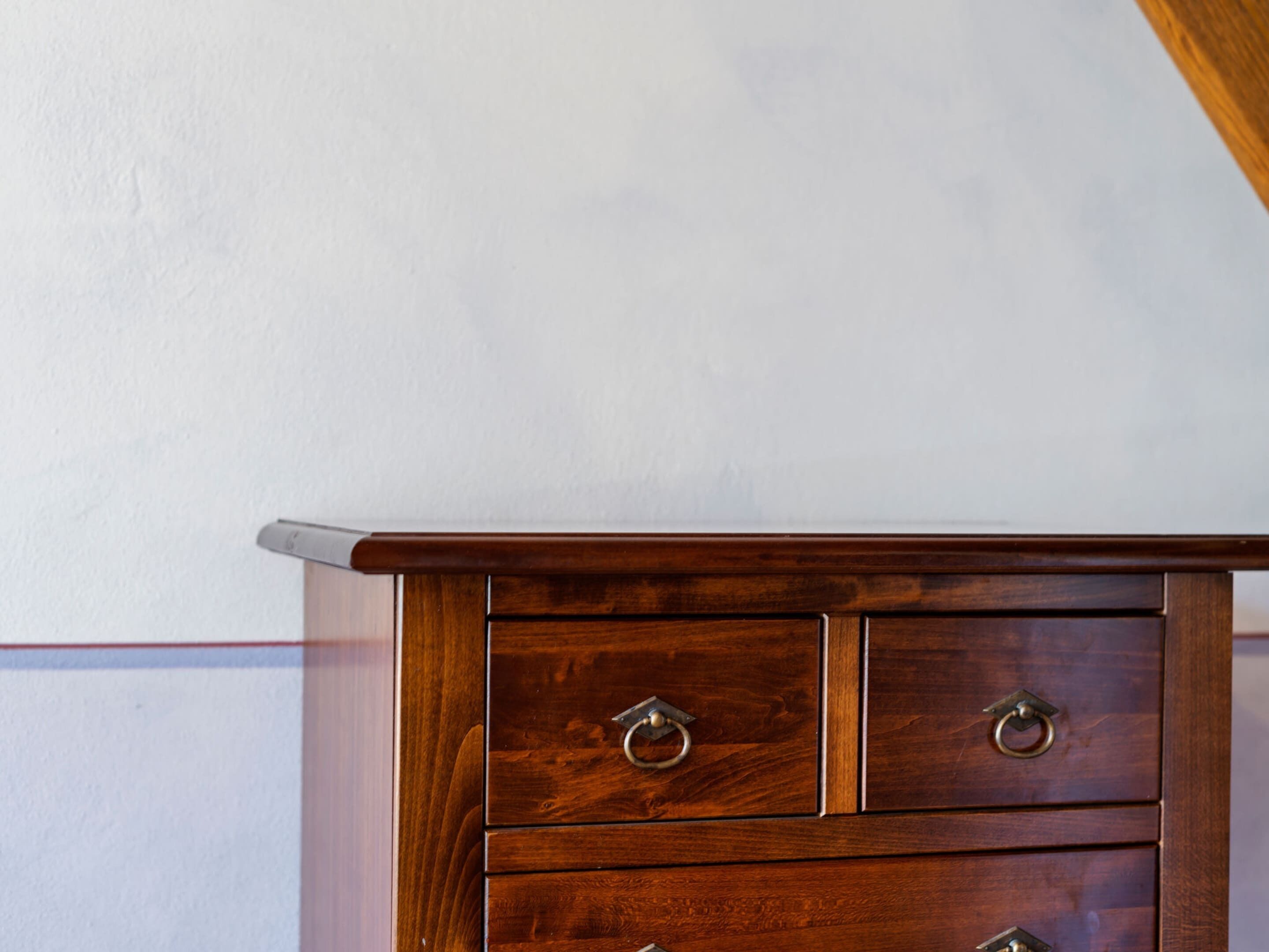 A wooden dresser with two drawers and a small cabinet, against a plain wall.