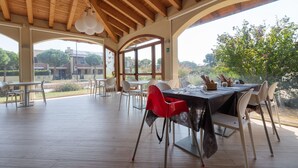 An outdoor dining area with wooden beams, white chairs, and a table set for two. - Comfort in Lido Delle Nazioni (Comacchio)