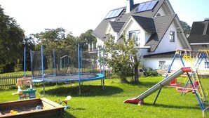 Un patio trasero con un trampolín, un tobogán y un columpio.