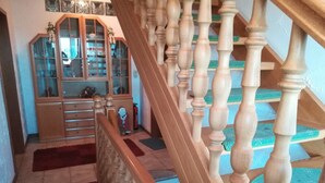 Una escalera con balaustres de madera y una alfombra roja que conduce a una habitación con un armario y una alfombra.