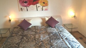 Una cama con colcha estampada, dos almohadas y dos mesitas de noche con lámparas.