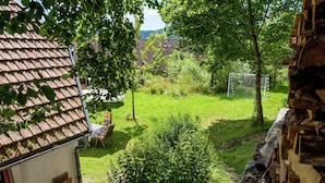 A rustic house with a tiled roof, a small garden with a wooden bench, and a pile of firewood. - Ferienhaus in Herrischried (Herrischried)