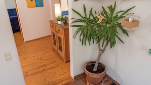 A wooden floor, a potted plant, a cabinet, and a wall with a branch and a hanging light fixture. - Ferienhaus in Herrischried (Herrischried)