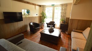Ein Wohnzimmer mit Flachbildfernseher, Ledersesseln, Couchtisch und Zimmerpflanze.