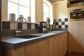 Uma cozinha com duas pias, uma cafeteira e um micro-ondas.