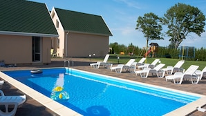 Ein rechteckiger Swimmingpool mit einer gefliesten Kante, umgeben von weißen Liegestühlen und einem kleinen Schwimmspielzeug im Wasser.