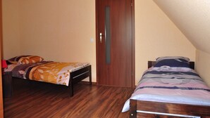Ein Schlafzimmer mit zwei Betten, Holzboden, einer Tür und einer geneigten Decke.