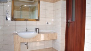 Ein Badezimmer mit einem weißen Waschbecken, einem Spiegel mit goldener Rahmung und einer Holztür.