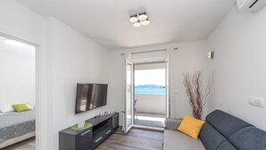 Ein modernes Wohnzimmer mit Flachbildfernseher, einer Couch und einem Balkon mit Blick.