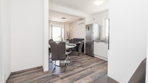 Eine moderne Küche mit integriertem Kühlschrank, ein Essbereich mit rundem Tisch und Stühlen sowie ein Fenster.