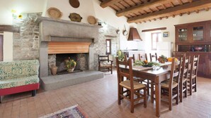 A rustic interior with a stone fireplace, wooden dining table, and chairs.