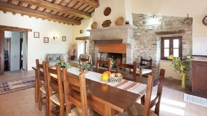 A dining area with a wooden table and chairs, a stone fireplace, and a rustic ceiling.