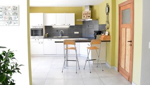 A modern kitchen with white cabinets, a stainless steel oven, and two foldable chairs.