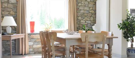 A dining area with a stone wall, a wooden table, and chairs.